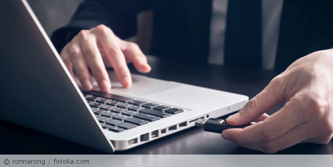 Man inserting a USB stick into a laptop.