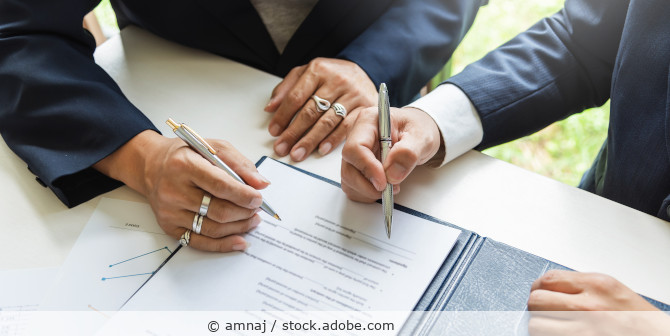Two people signing a document.