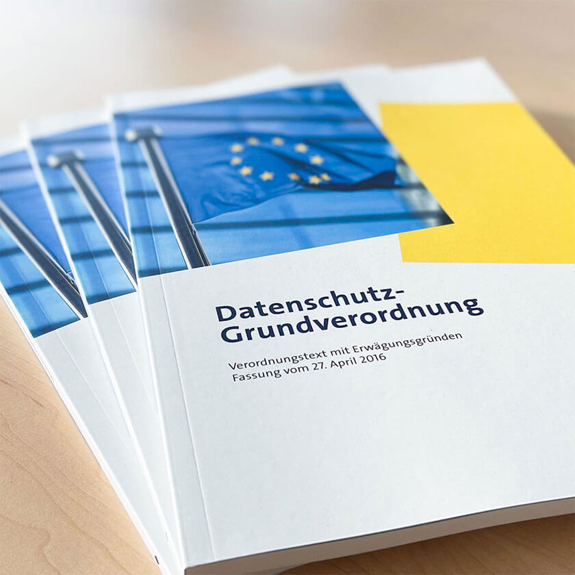 Die DSGVO als gebundene Hefte im Design der DSN Akademie liegen auf einem Tisch.